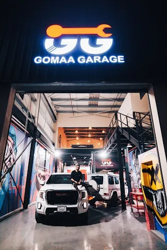 The lit Gomaa Garage sign above the workshop entrance